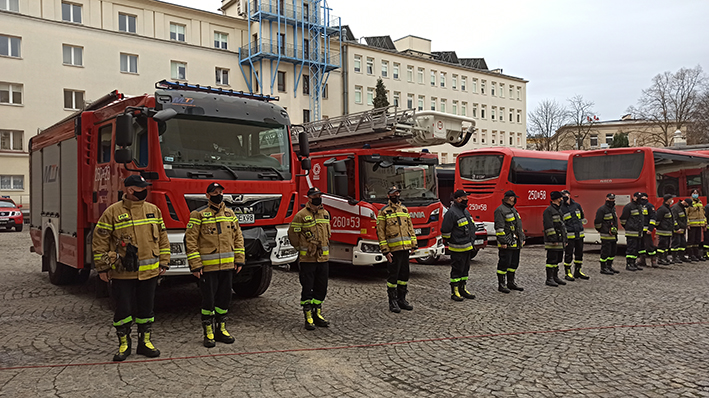 Wyjazd polskich strażaków na Słowację. Strażacy w szeregu na tle samochodów pożarniczych