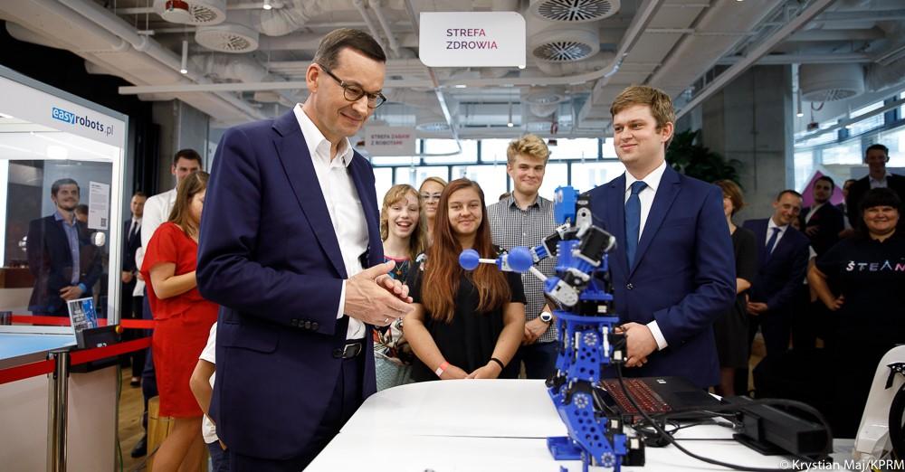 Premier Mateusz Morawiecki ogląda robota zbudowanego przez młodych.