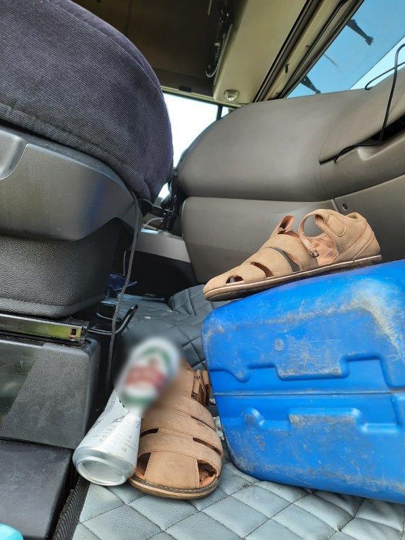Pusta puszka po piwie, kanister i buty w kabinie ciężarówki 