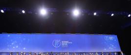 Szczyt Cyfrowy ONZ – IGF 2021. Uczestnicy stoją na scenie. Z tyłu ekran z logo IGF 2021. Na górze oświetlenie. Fot. PAP