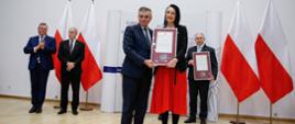 Zdjęcie grupowe wojewody lubelskiego z osobami uhonorowanymi dyplomami uznania.