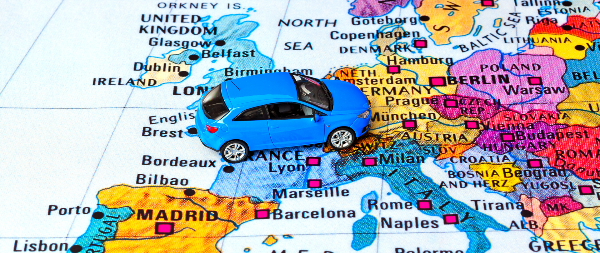 Zabawkowy, niebieski samochód na kolorowej mapie Europy.