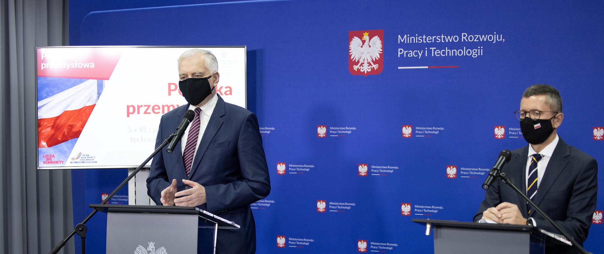 Zdjęcie przedstawia stojących za mównicami wicepremiera Jarosława Gowina oraz wiceministra Roberta Tomanka podczas konferencji prasowej w MRPiT nt. Polityki Przemysłowej Polski