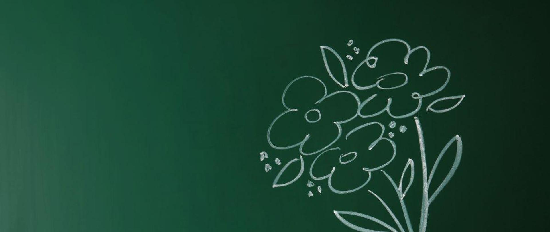 Na zielonej tablicy bukiet kwiatów narysowany białą kredą i zdjęcie ręki dziecka.