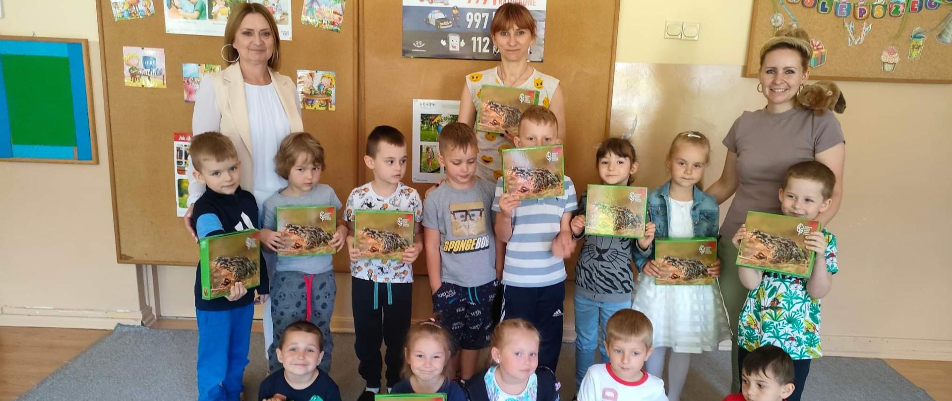 Grupa przedszkolaków na pamiątkowym wspólnym zdjęciu - każde dziecko ma puzzle z ropuchą