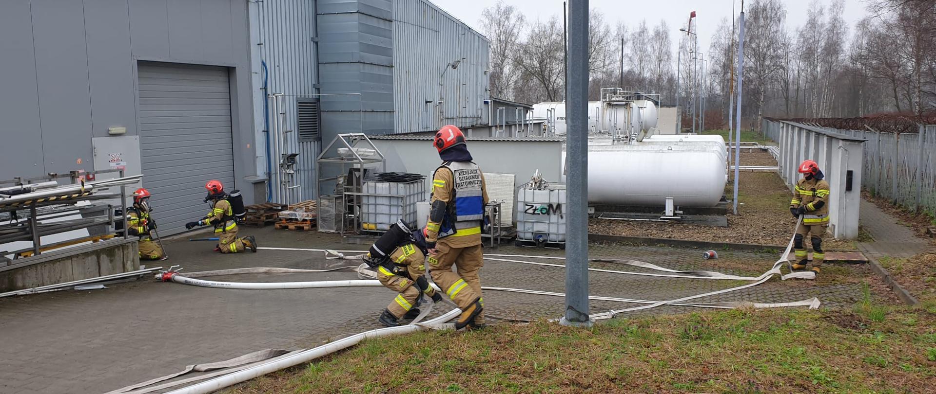 Na zdjęciu strażacy przed wejściem do budynku zakładu Jago-Pro wykonujący ćwiczenie polegające na rozwinięciu linii gaśniczej.