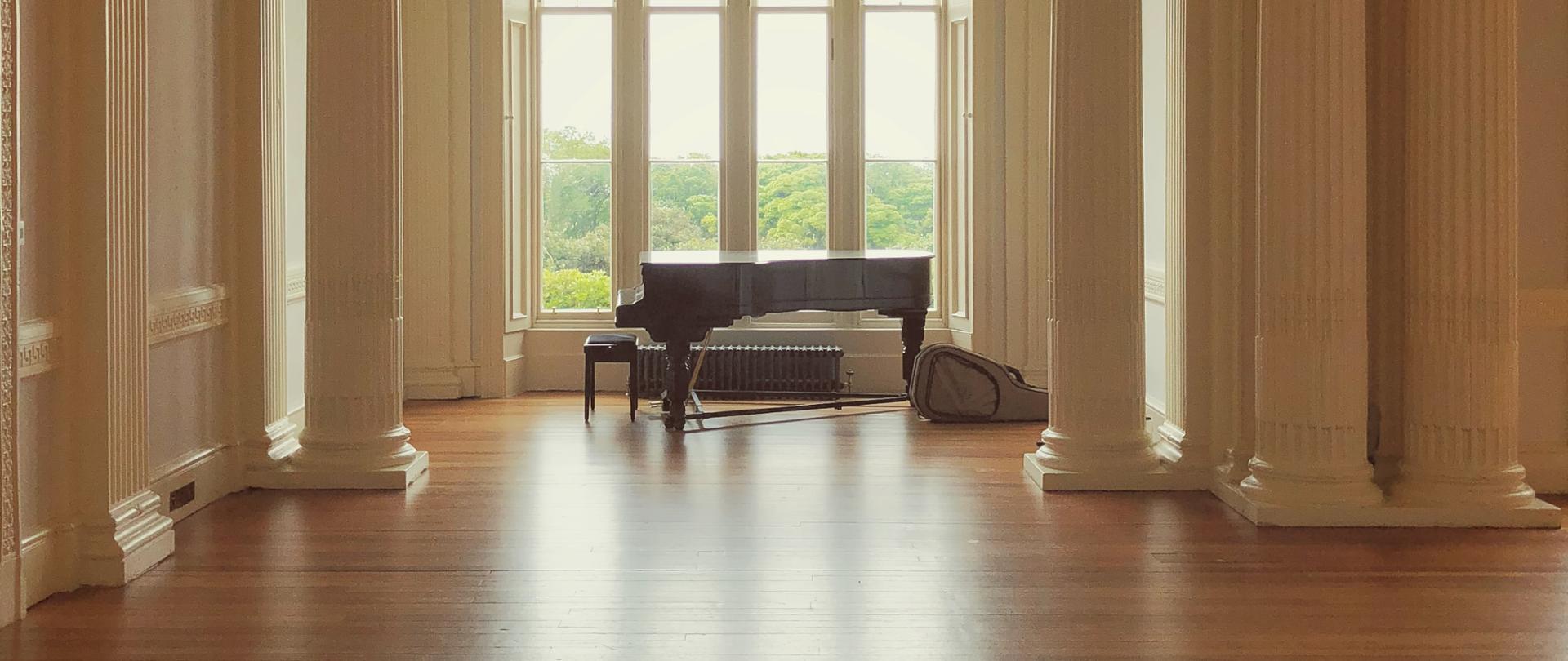 zdjęcie przedstawiające dużą salę z fortepianem ustawionym na tle okna
