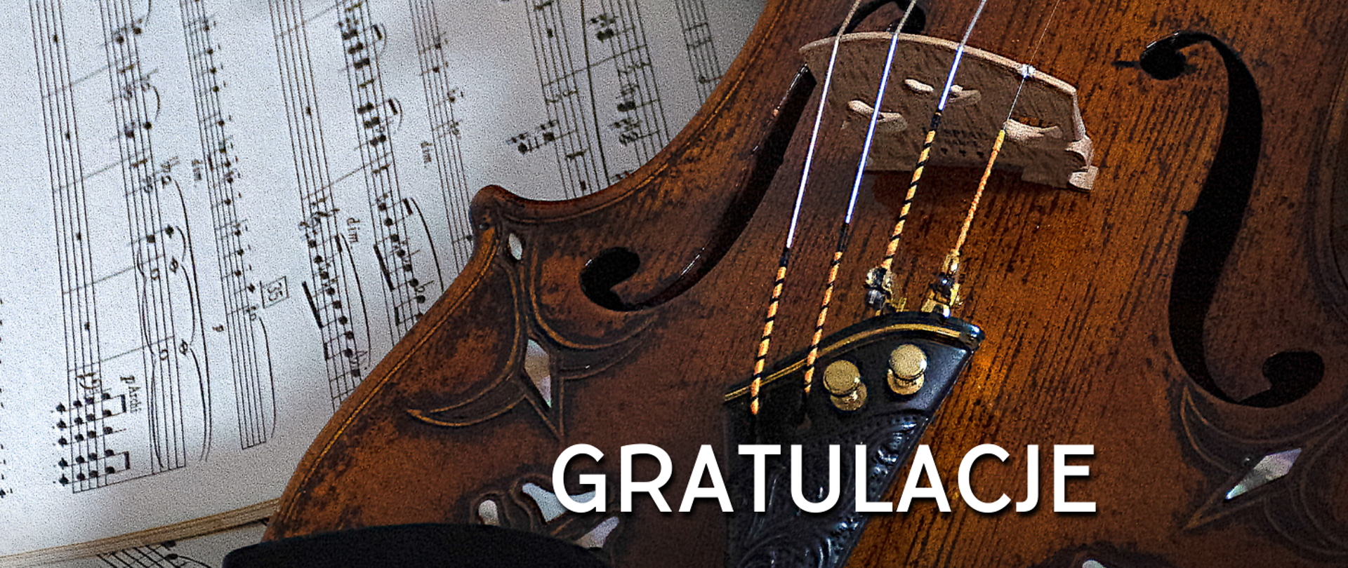 Na zdjęciu po lewej stronie kartka z nutami na pięciolinii, a po prawej stronie skrzypce. Na skrzypcach biały napis "gratulacje".