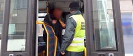 Umundurowany funkcjonariusz zachodniopomorskiej Inspekcji Transportu Drogowego stoi w przednich drzwiach wejściowych do autobusu, trzyma w ręku alkomat przesiewowy i sprawdza trzeźwość kierowcy.
