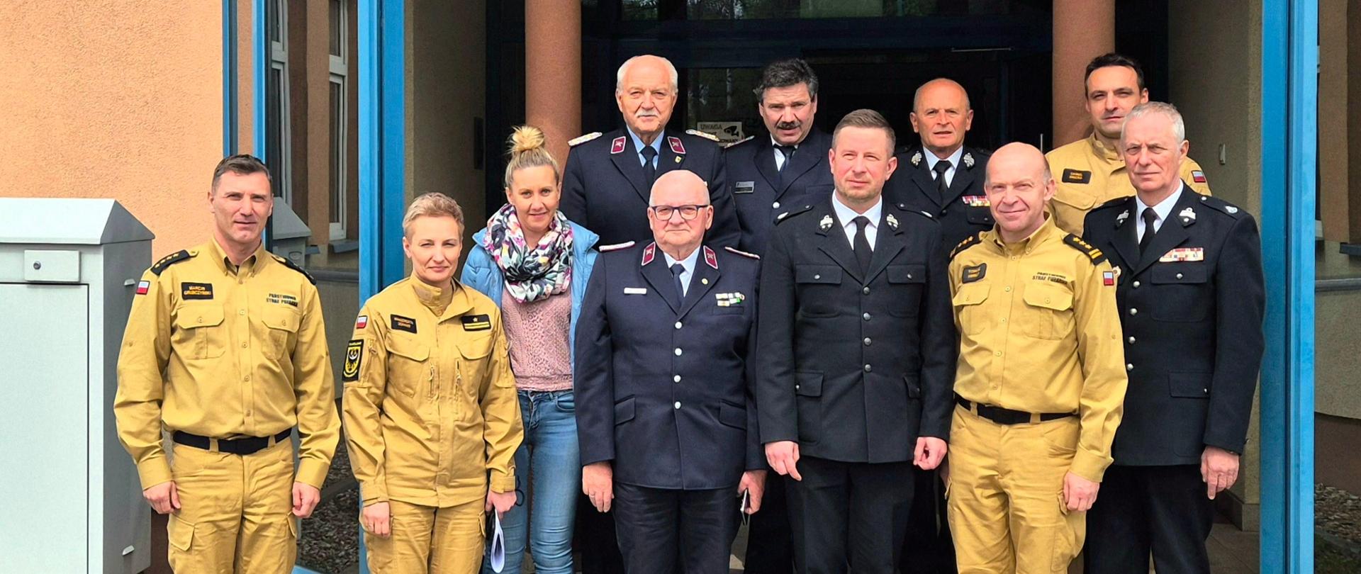 Zdjęcie grupowe polskich i niemieckich strażaków ubranych w mundury. W tle zarys budynku