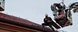 Strażak podczas ćwiczeń ewakuuje poszkodowanego z dachu
