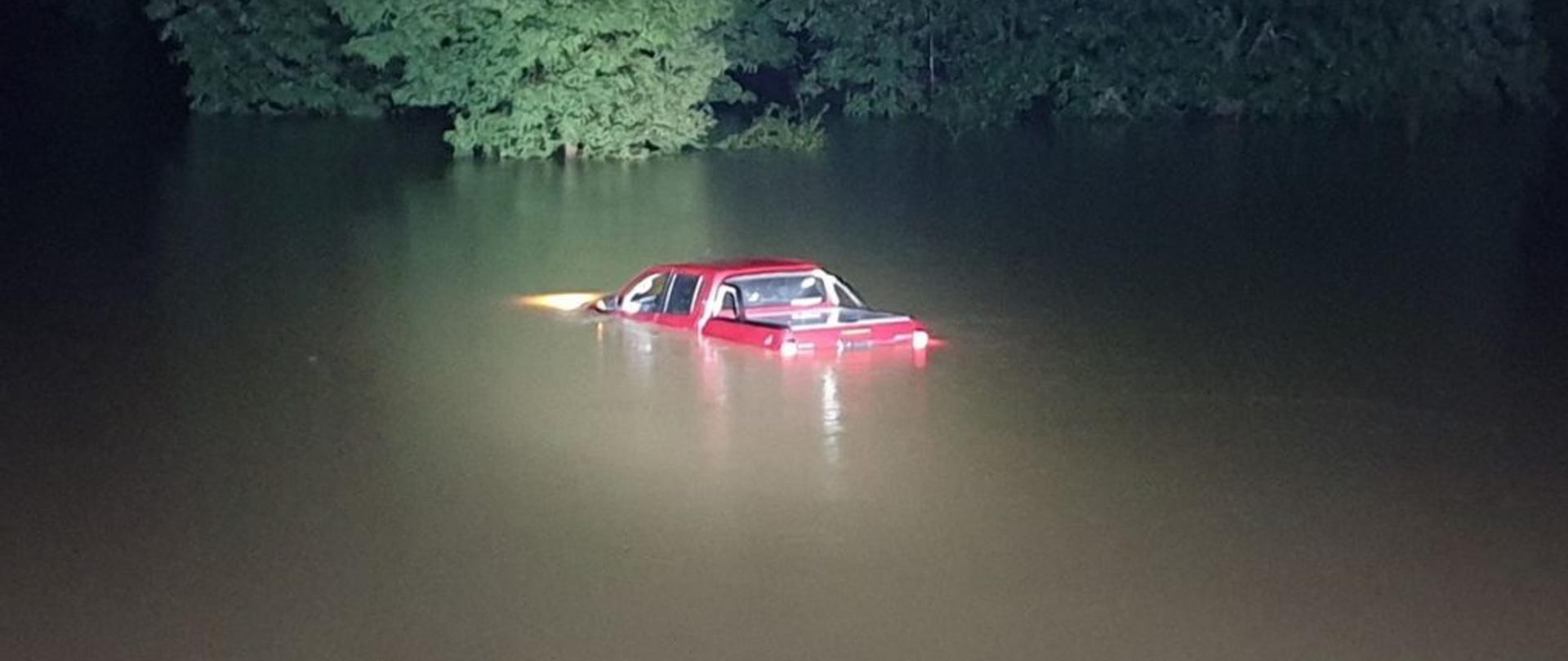 Zdjęcie przedstawia samochód osobowy, który wjechał na zalaną drogę.