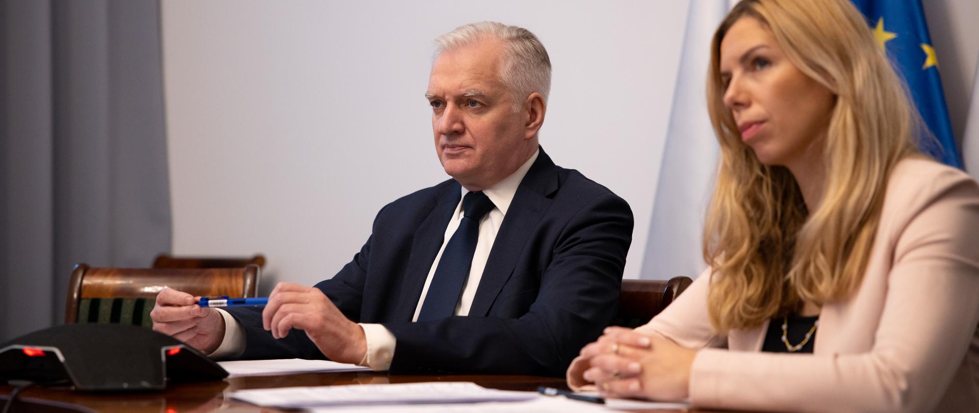 Od lewej, za stołem konferencyjnym, siedzą Jarosław Gowin i Anna Kornecka. Za nimi flagi polska i unijna, przed nimi notatki i mikrofon.