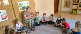Grupa przedszkolaków siedzących w kręgu w sali przedszkolnej słucha opowieści o mazowieckiej przyrodzie