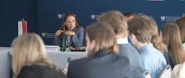 Minister funduszy i polityki regionalnej Katarzyna Pełczyńska-Nałęcz siedzi przy stole, obok niej studenci Stosunków Międzynarodowych i Europeistyki 