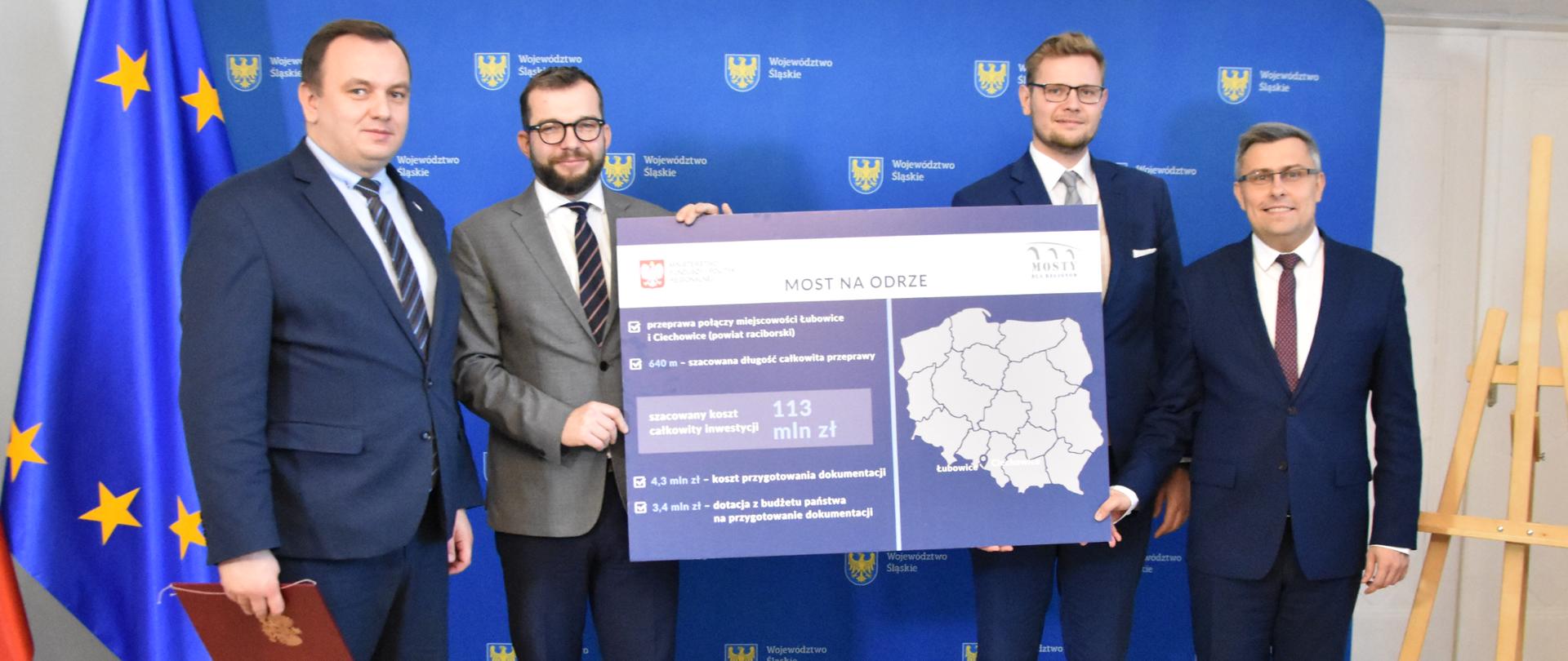 Zdjęcie, przedstawiające czterech mężczyzn. Dwóch z nich trzyma w dłoni planszę z napisem "Most na Odrze". Wśród osób jest Minister Puda, Marszałek Śląski i Wojewoda Śląski. 