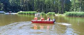 Na zdjęciu strażacy oraz dzieci w łodzi motorowej płynący po jeziorze