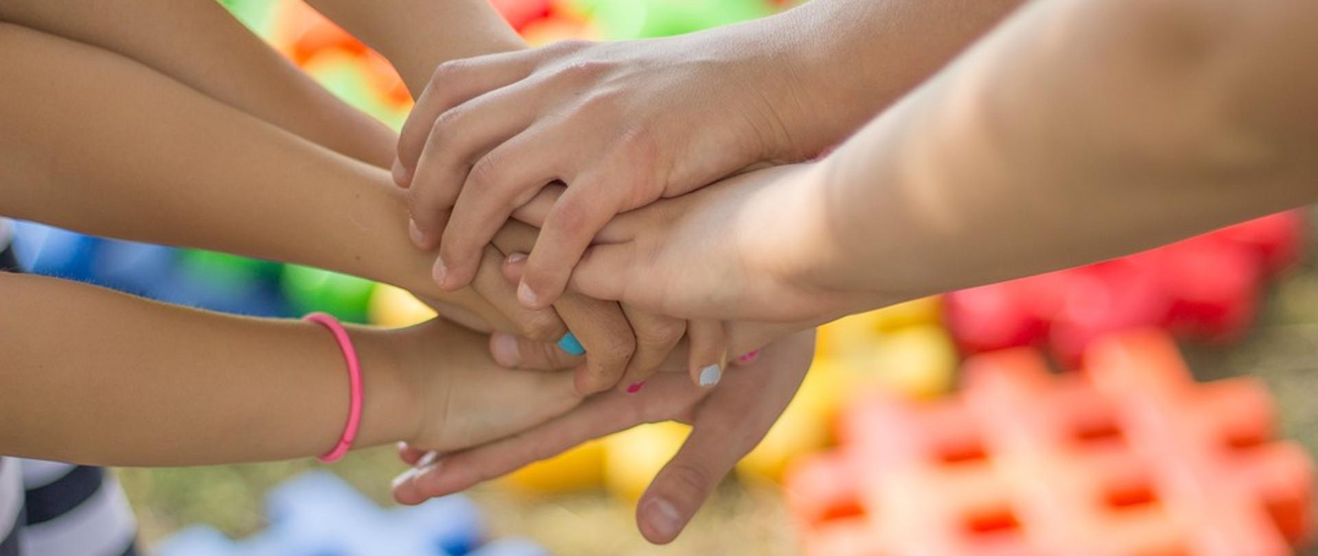 Uścisk rąk dzieci na tle kolorowych klocków
