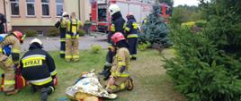 Na zewnątrz strażacy w punkcie medycznym udzielają pomocy poszkodowanemu