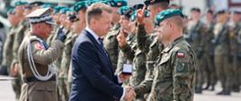 Minister obrony narodowej gratuluje żołnierzowi w mundurze.