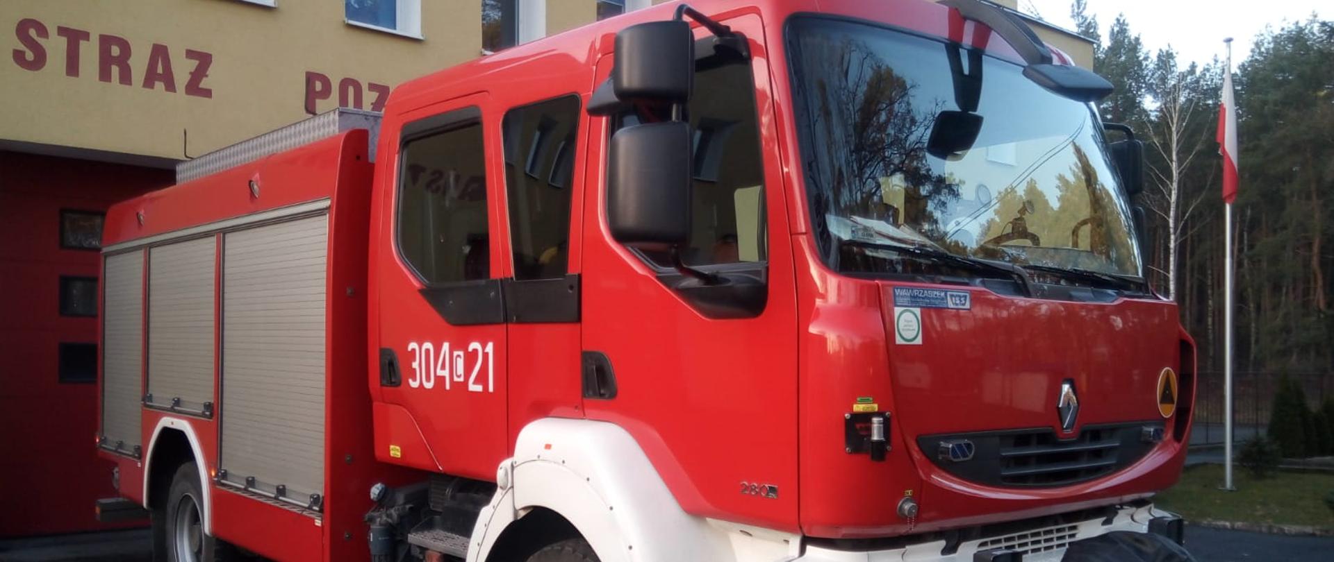 Samochód strażacki ciężarowy ratowniczo-gaśniczy Jednostki Ratowniczo-Gaśniczej nr 4 w Bydgoszczy, podwozie marki Renault, w tle budynek jednostki.