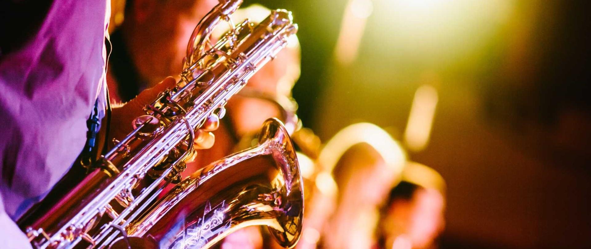 fotografia przedstawia saksofon trzymany w rękach muzyka