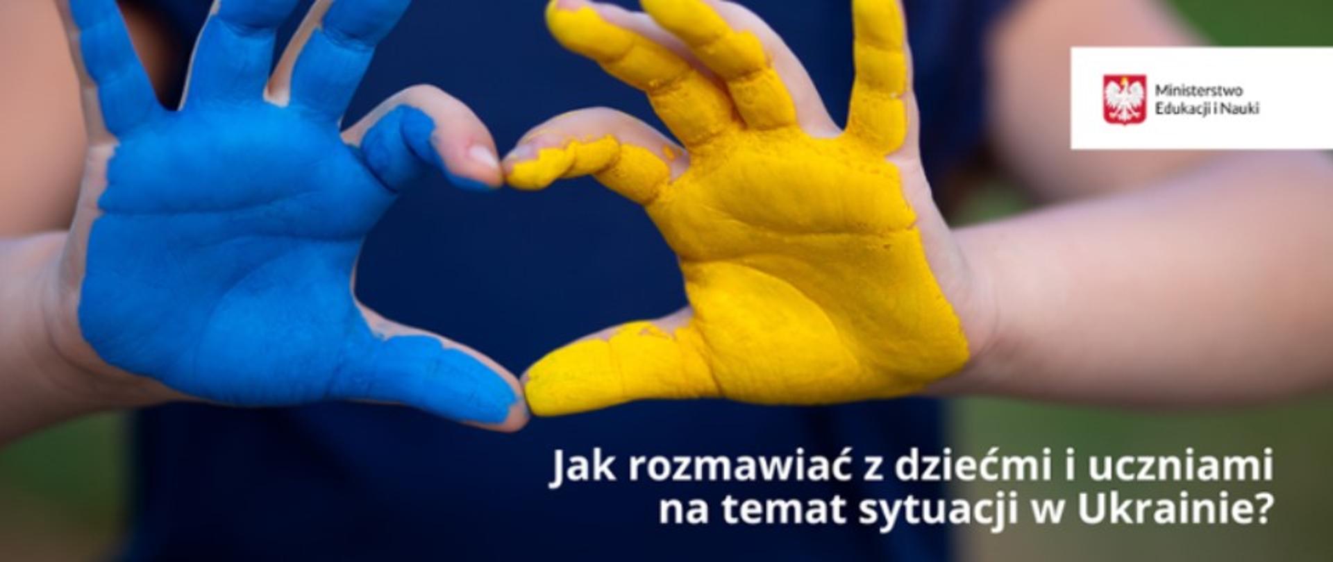 Plakat przedstawia otwarte dłonie dziecka - kciuki i palce wskazujące złożone w kształt serca. Spód lewej dłoni pokryty żółta farbą, prawej niebieską. Wszystko na tle granatowej koszulki dziecka. Z prawej strony w górnym rogu - logo MEN, poniżej napis: Jak rozmawiać z dziećmi i uczniami na temat sytuacji na Ukrainie. 