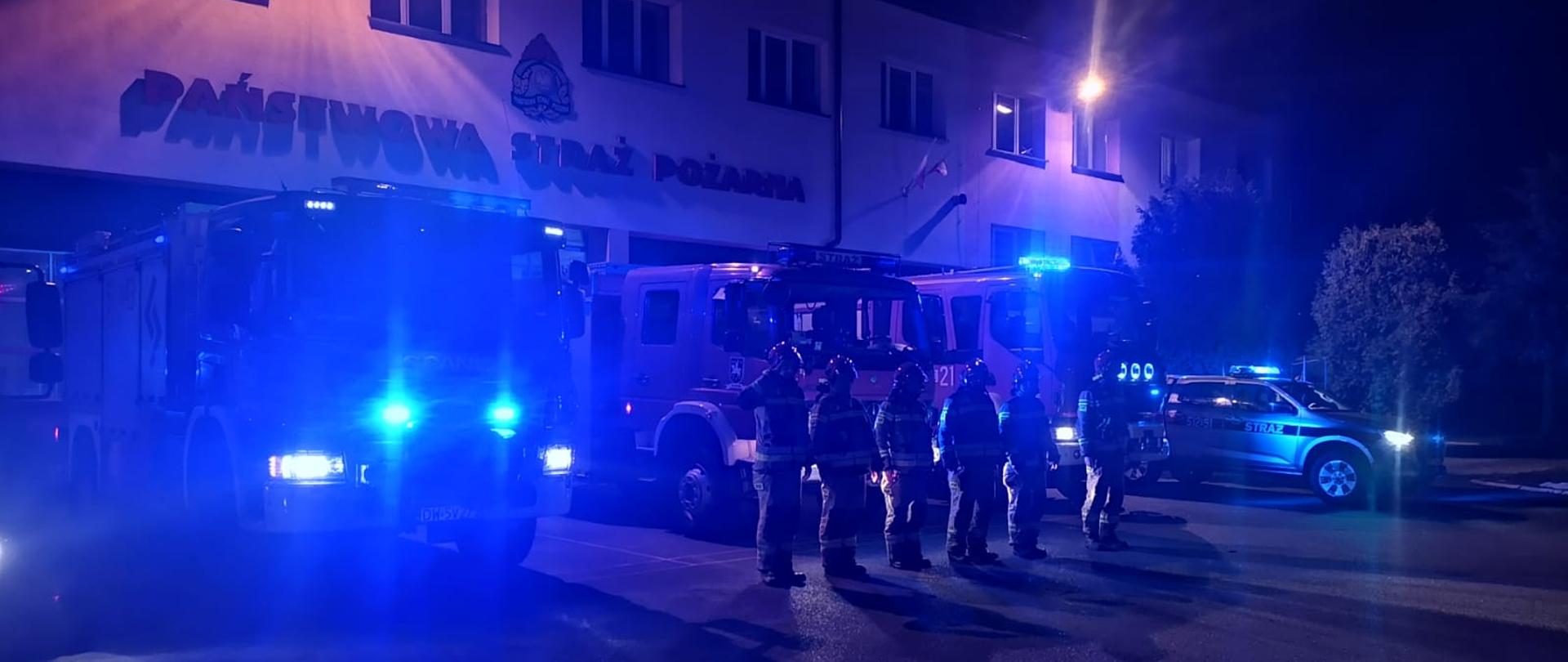 Strażacy oddają honory zmarłych druhom z Czernikowa. Na zdjęciu w porze nocnej dobre widoczne niebieskie sygnały alarmowe