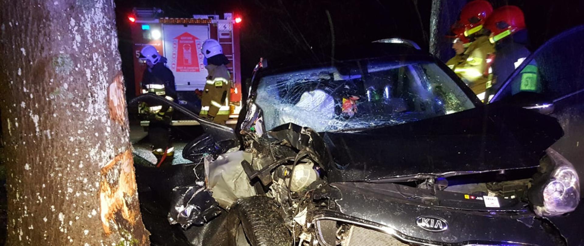 Wypadek samochodu osobowego na drodze wojewódzkiej nr 172 przy miejscowości Łęknica - pojazd osobowy marki KIA, koloru czarnego uderzył w drzewo, rozbity stoi częściowo na jednym pasie drogi oraz na poboczu.