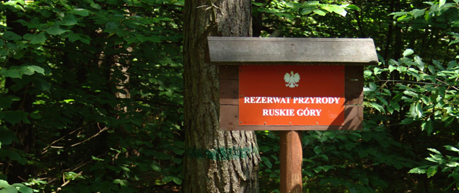 Tablica urzędowa oznaczająca rezerwat, w tle las