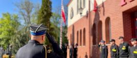 Moment podniesienia Flagi Państwowej Rzeczypospolitej Polskiej. Strażacy w czasie uroczystej zbiórki oddają honor.