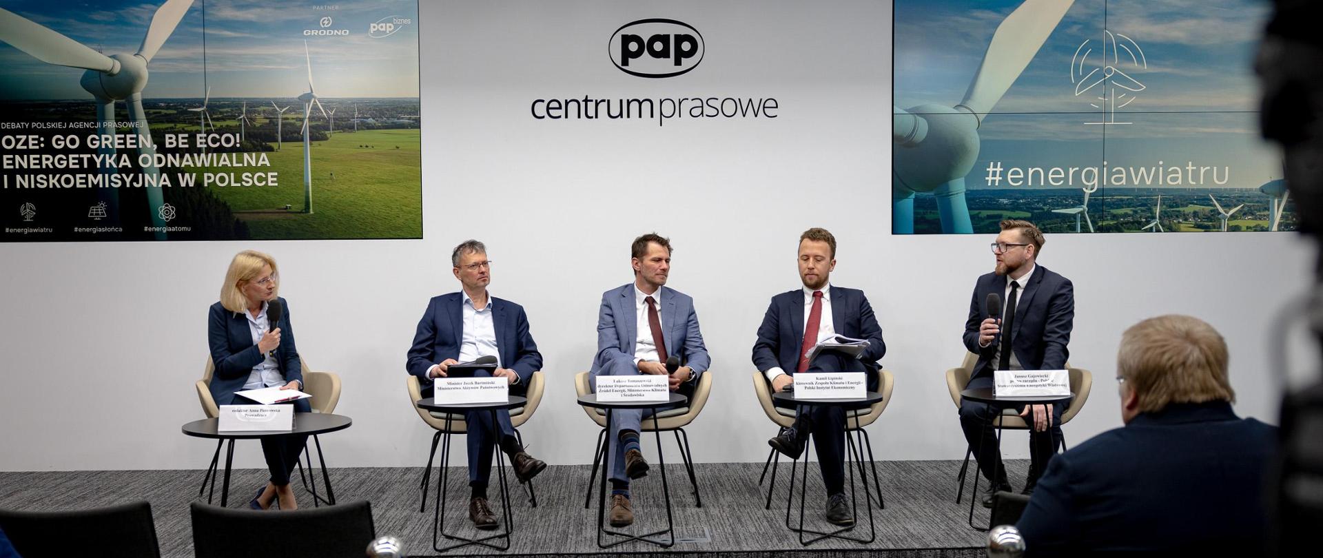Na zdjęciu siedzi pięć osób. Drugi od lewej siedzi wiceminister Jacek Bartmiński w granatowym garniturze. W tle napis: PAP, centrum prasowe. 