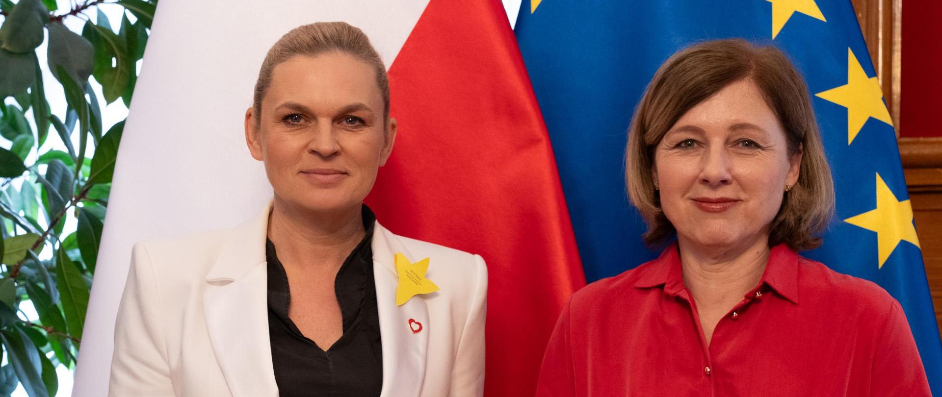 Minister Barbara Nowacka i Věrą Jourovą stoją na tle flag Polski i UE.