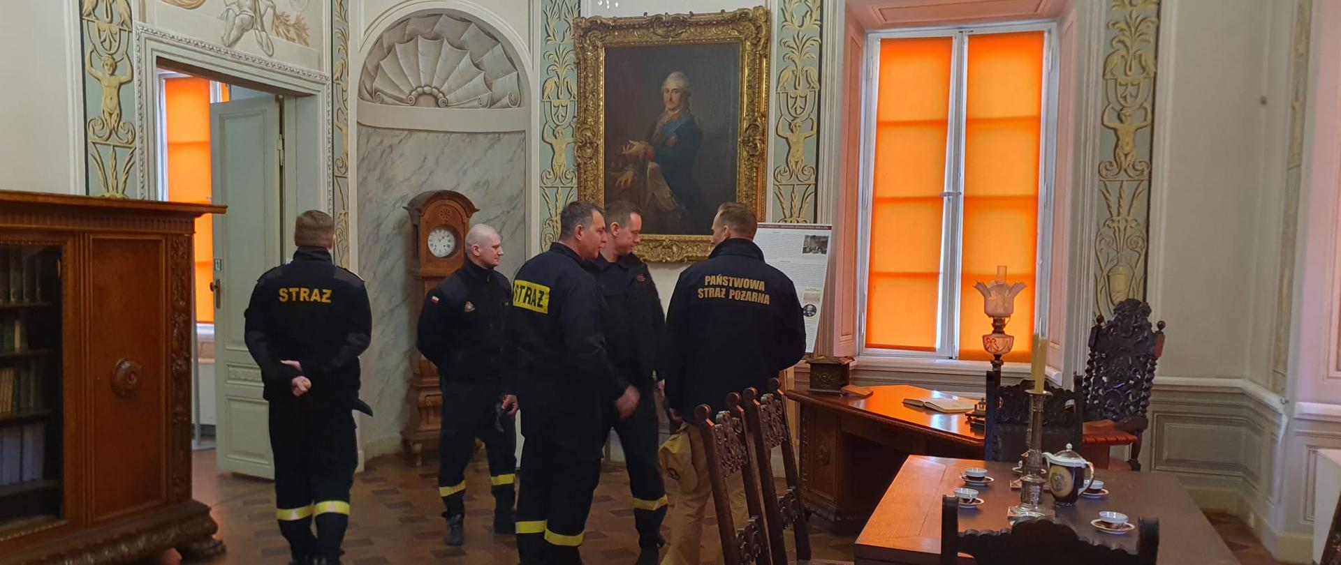 Pomieszczenie muzeum w którym znajduje się sześciu strażakow prowadzących rozpoznanie obiektu, w pomieszczeniu znajdują się zabytkowe meble