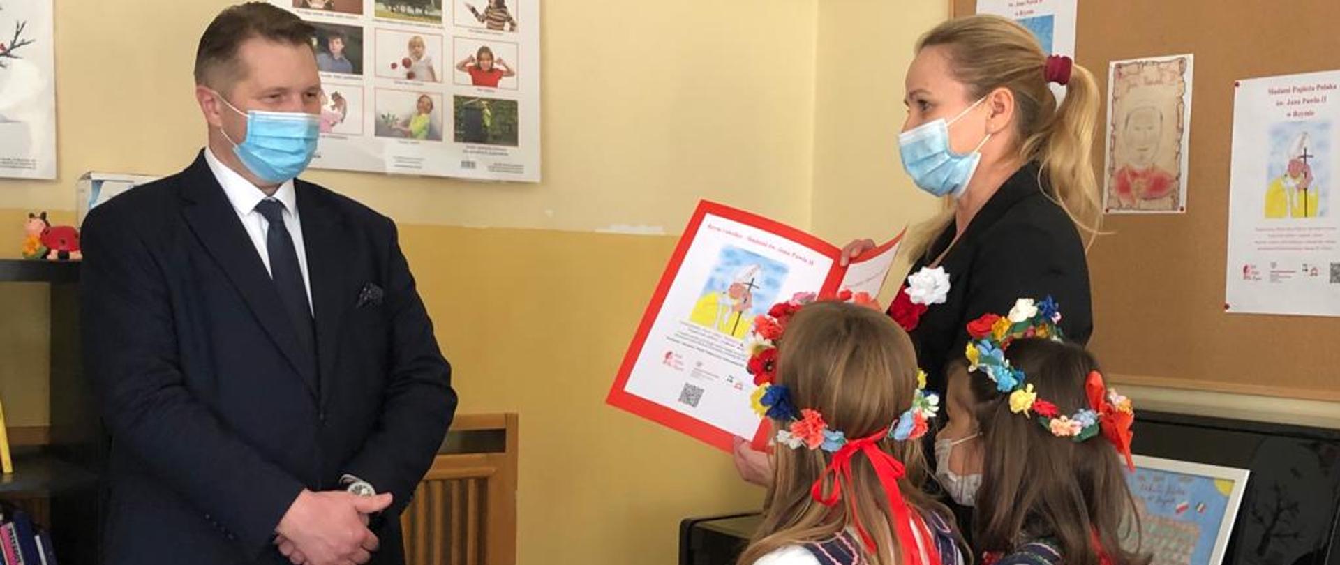 Wizyta Ministra Edukacji i Nauki we Włoszech, minister Przemysław Czarnek przyjmuje upominek z rąk nauczycieli i uczniów Szkoły Polskiej w Rzymie.