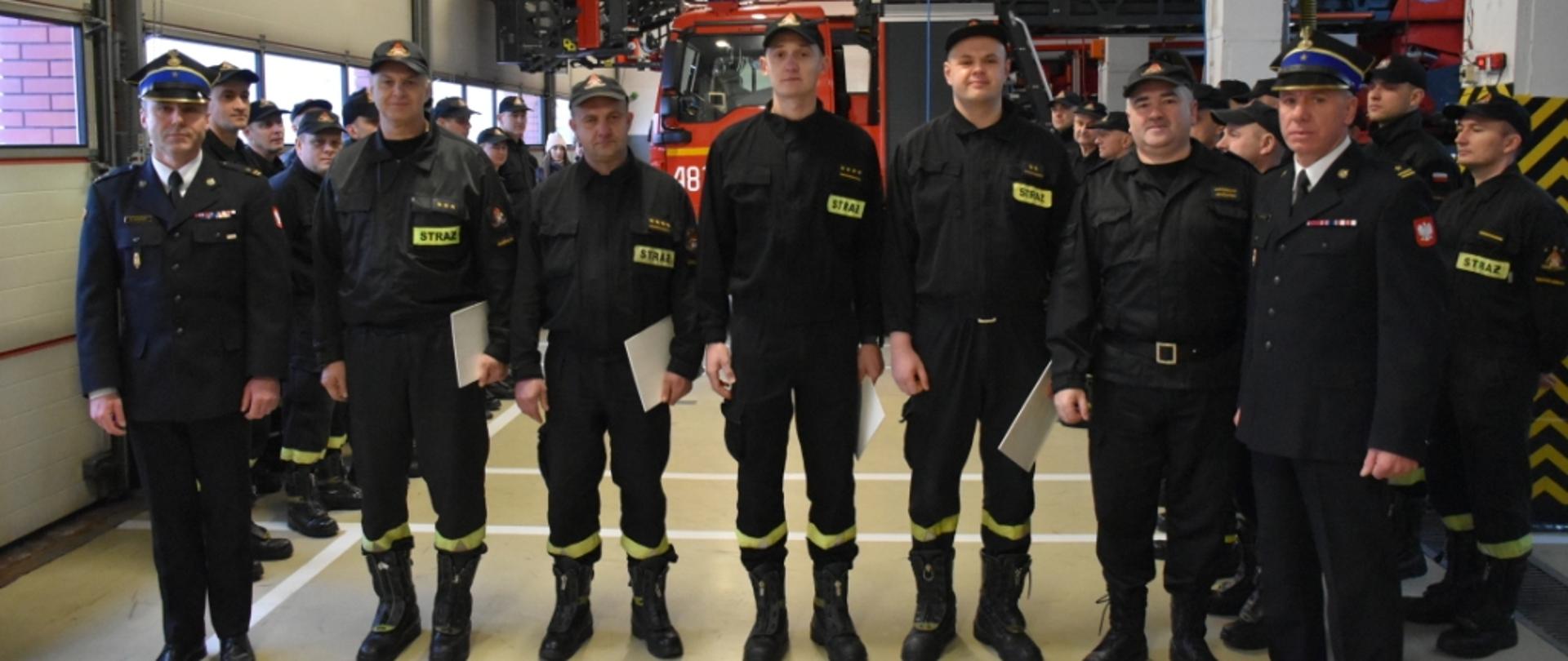 Wspólne zdjęcie komendanta i jego zastępcy wraz z awansowanymi strażakami.