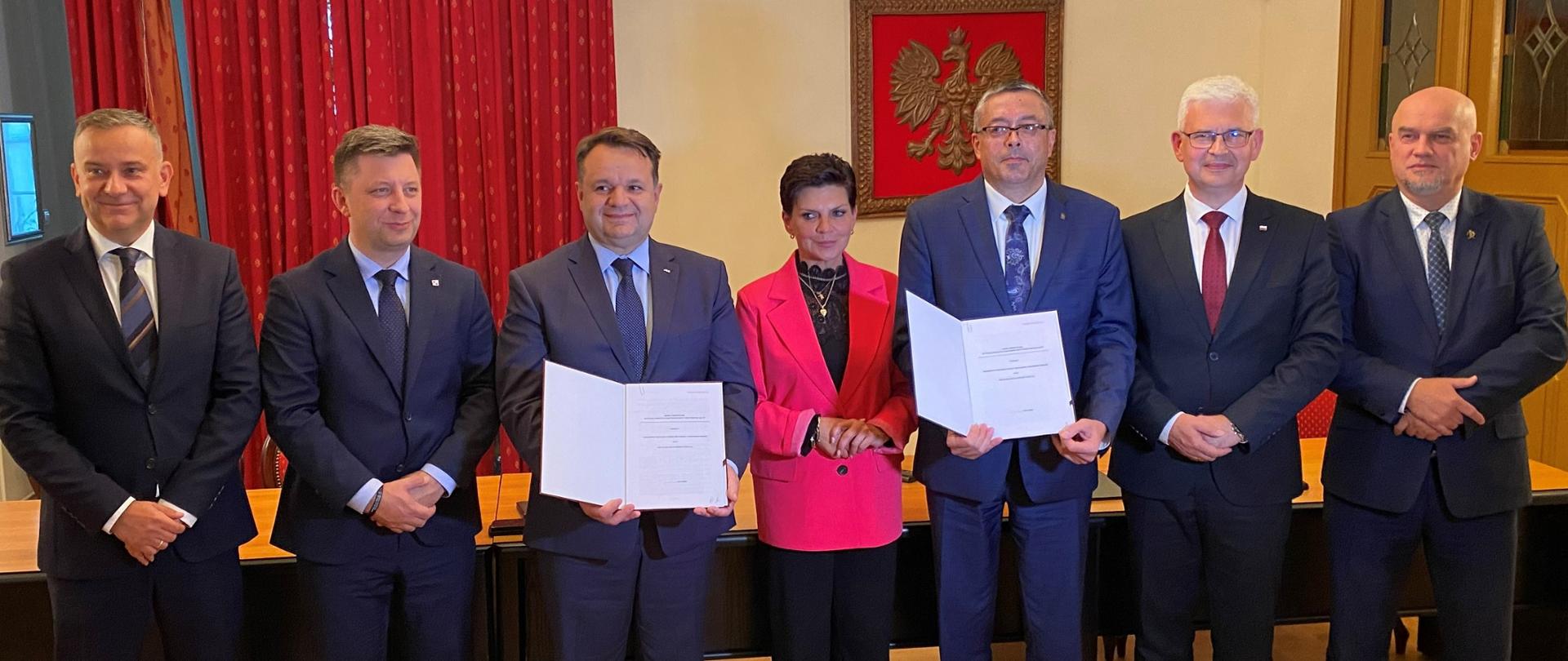 Artur Michalski, zastępca prezesa zarządu NFOŚiGW z Beneficjentem okazują podpisane umowy. Zdjęcie grupowe