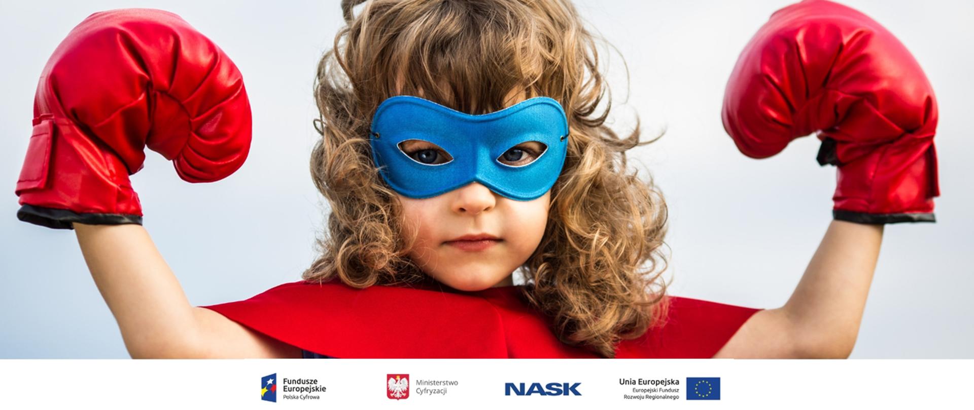 Zdjęcie przedstawia dziewczynkę w kostiumie superbohaterki z maską na oczach i rękawicami bokserskimi na dłoniach - rączki ma uniesione w górę w geście symbolizującym siłę. U dołu znajduje się pasek logotypów: Europejskie Fundusze Polska Cyfrowa, Ministerstwo Cyfryzacji, NASK i Unia Europejska Europejski Fundusz Rozwoju Regionalnego.