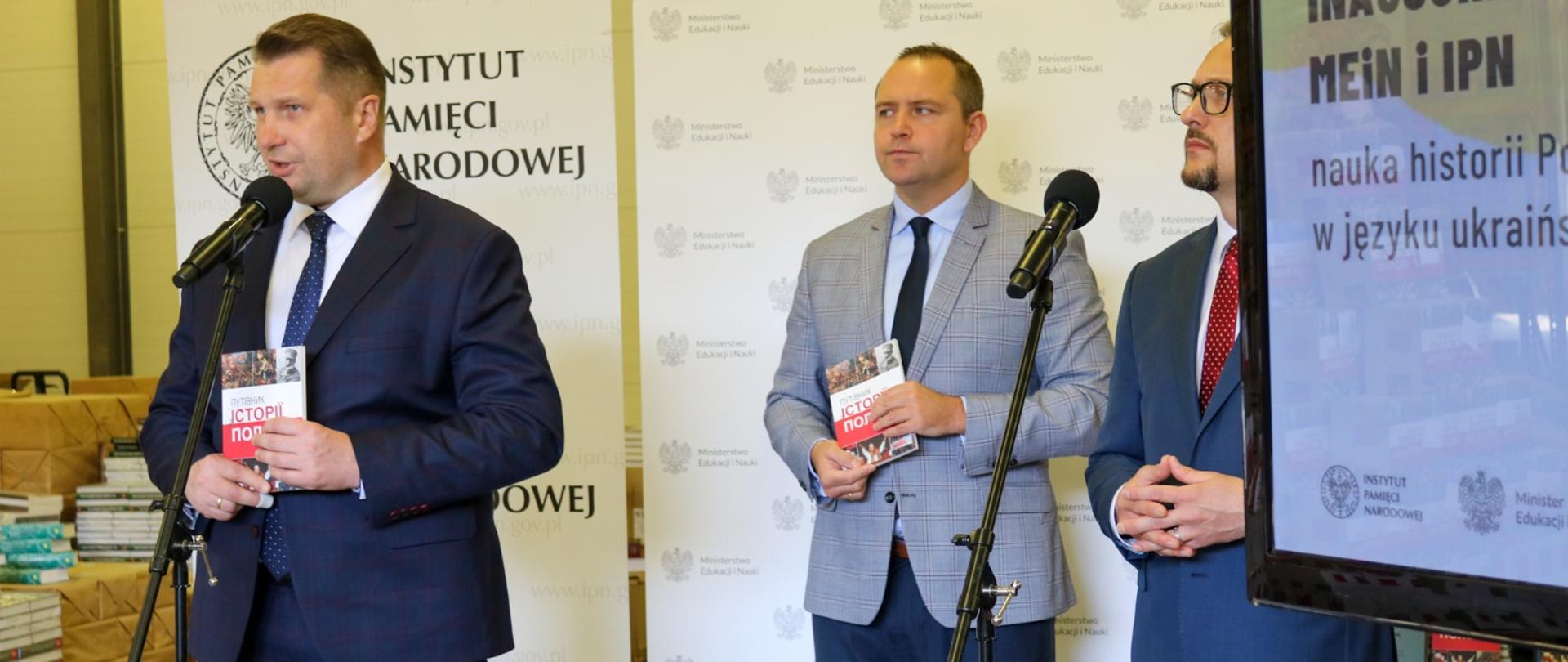 Minister Przemysław Czarnek prezentuje książkę. Z tyłu za nim stoją przedstawiciele IPN