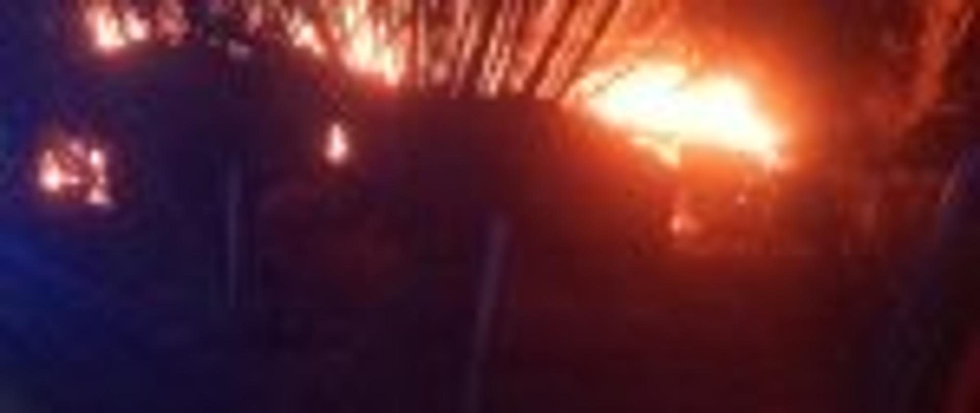 Zdjęcie przedstawia płonący dach obory. Fotografia wykonana z wnętrza samochodu gaśniczego.