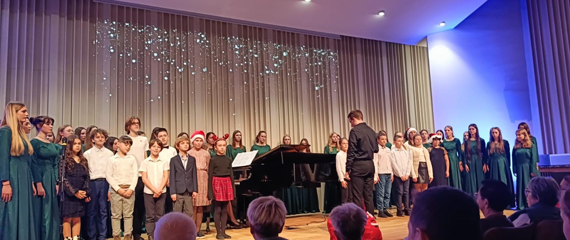 Zdjęcie prezentujące występ uczniów podczas koncertu bożonarodzeniowego, który odbył się w nowej sali koncertowej.