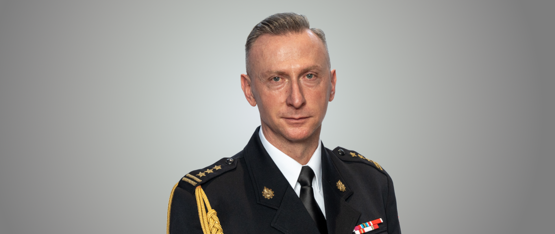 Zdjęcie portretowe przedstawia zastępce śląskiego komendanta wojewódzkiego PSP st. bryg. Damiana Legierskiego w mundurze wyjściowym ze sznurem galowym
