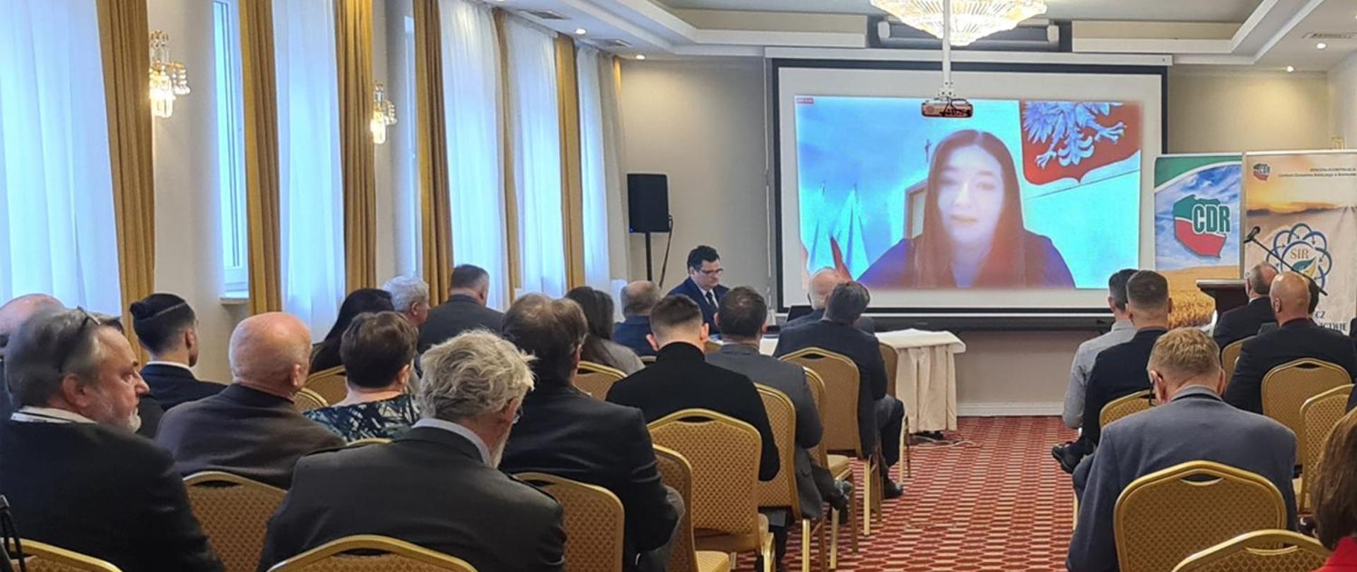 Wiceminister Anna Gembicka widoczna na telebimie podczas Forum