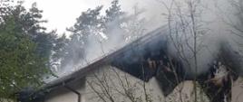 Dom, w którym powstał pożar. Widoczna zniszczona elewacja i jasny dym.