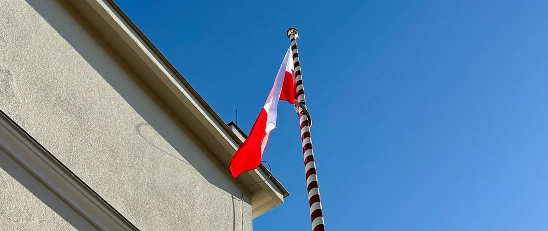Zdjęcie przedstawia Flagę Rzeczypospolitej Polskiej zawieszoną na maszcie z okazji obchodów Dnia flagi państwowej. 