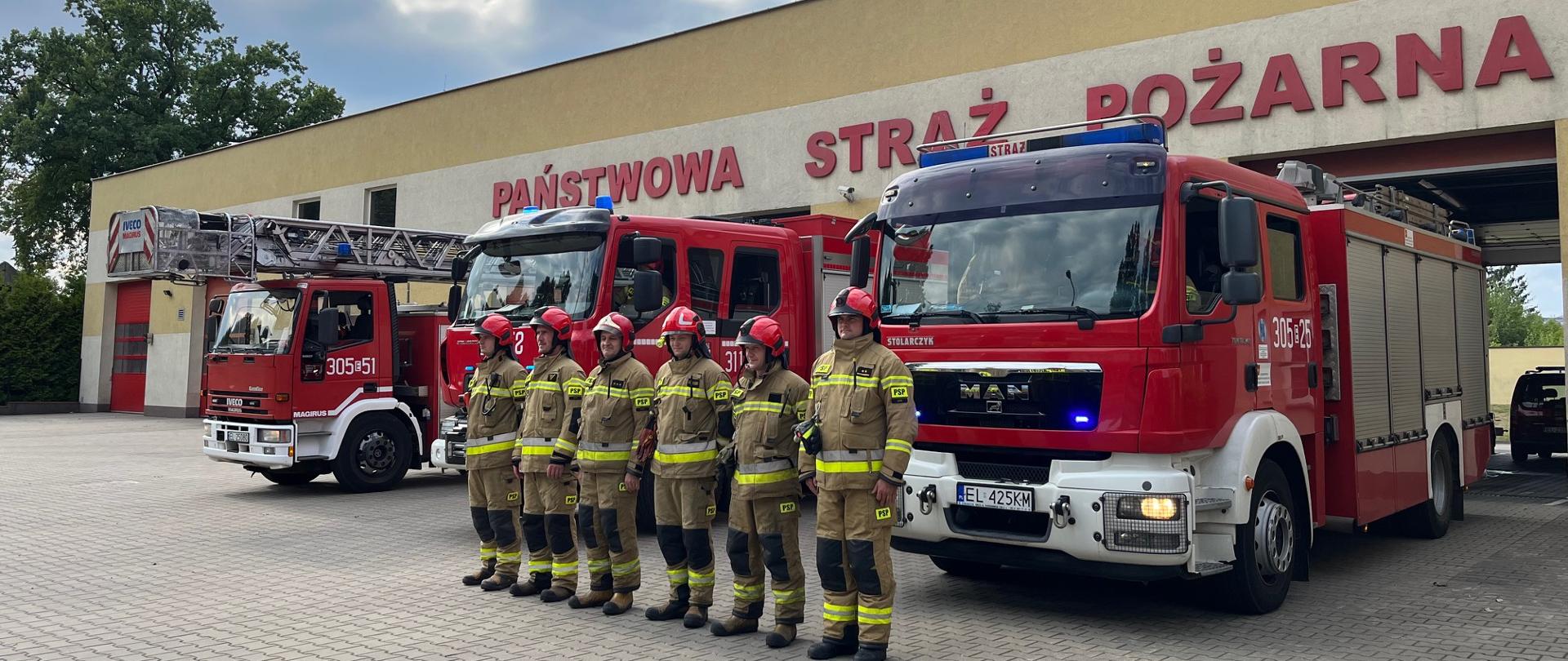 Strażacy stojący w rzędzie na baczność przed samochodami pożarniczymi oddają hołd powstańcom warszawskim