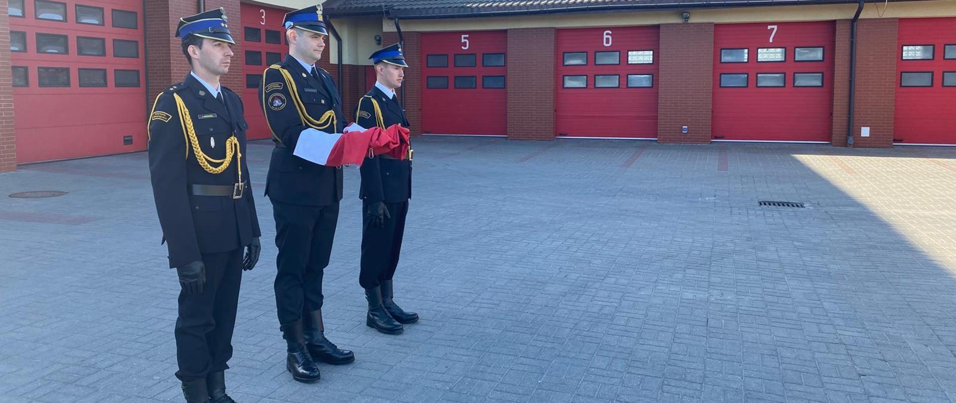 Poczet flagowy Komendy Powiatowej Państwowej Straży Pożarnej w Rypinie oczekuje na przemarsz po placu Jednostki Ratowniczo-Gaśniczej, w celu zawieszenia Flagi Państwowej na maszcie.