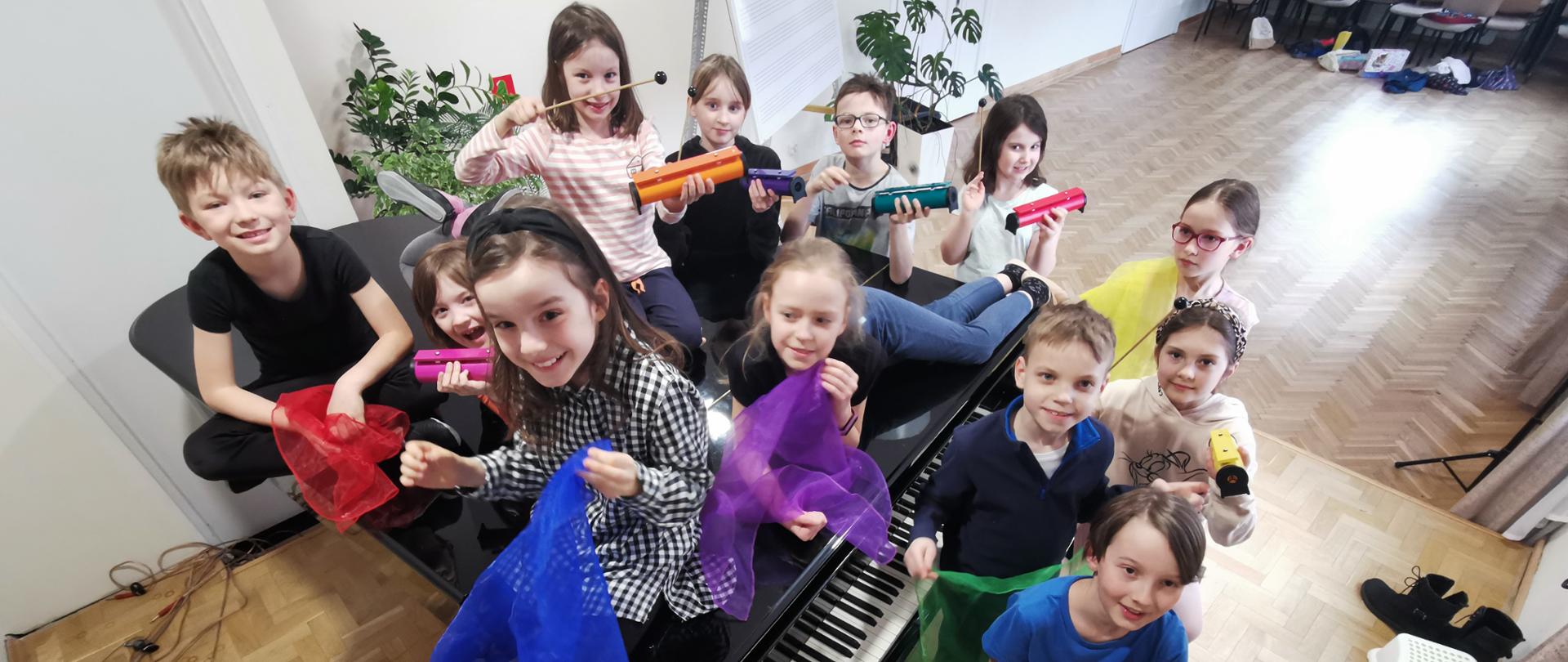 Zdjęcie grupy uczniów z instrumentami perkusyjnymi i kolorowymi chustami.