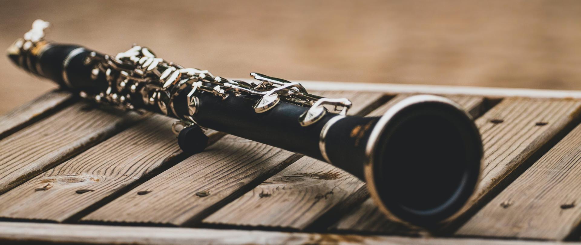 Fotografia przedstawia klarnet leżący na jasnych deseczkach