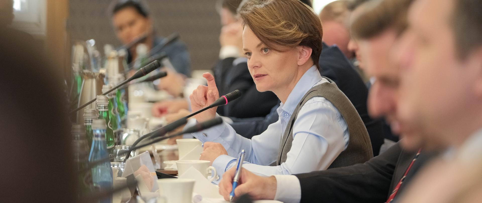 Wiceminister Jadwiga Emilewicz siedzi przy stole i mówi do mikrofonu.